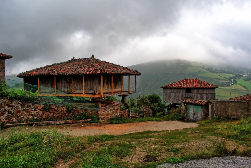 Hórreos asturianos tradicionales en un paisaje neblinoso, símbolos de la herencia arquitectónica de Asturias.