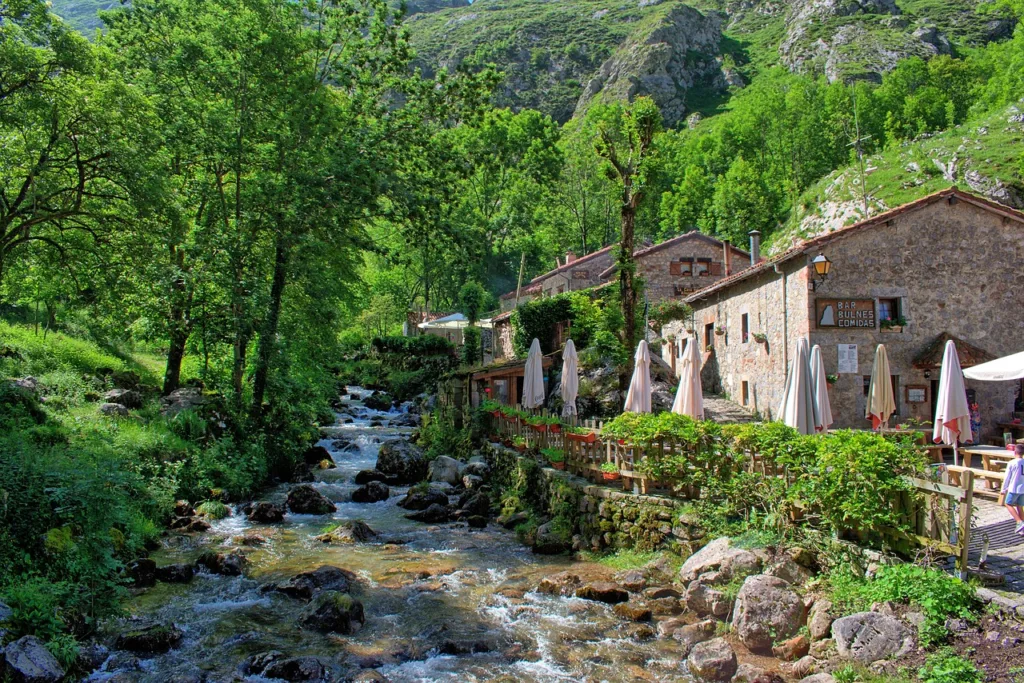 Edificación rústica junto a un arroyo en Asturias, rodeada de exuberante verde.